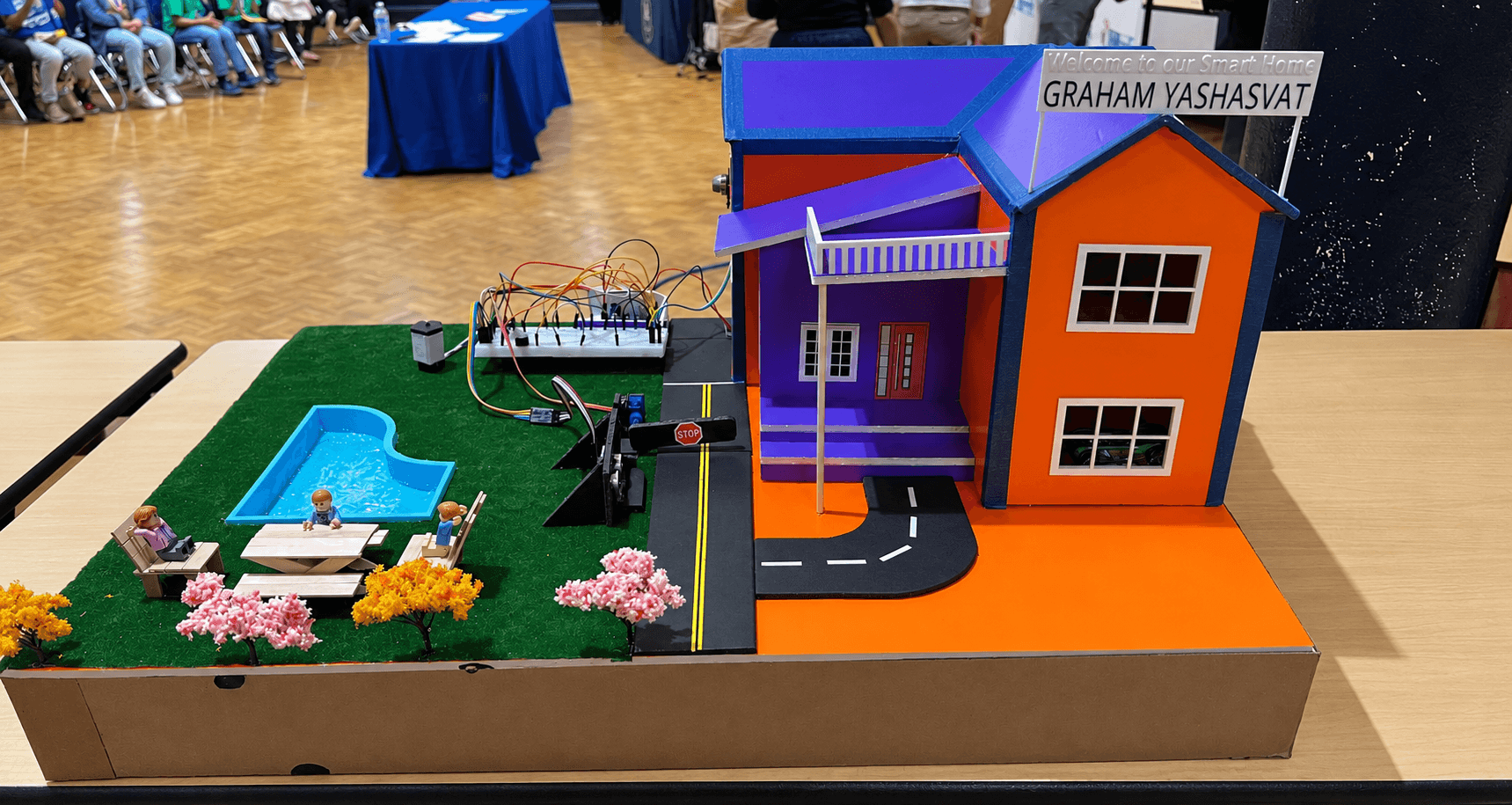 Smart home model with an automated entry barrier, pool, sensors, and exposed control electronics
